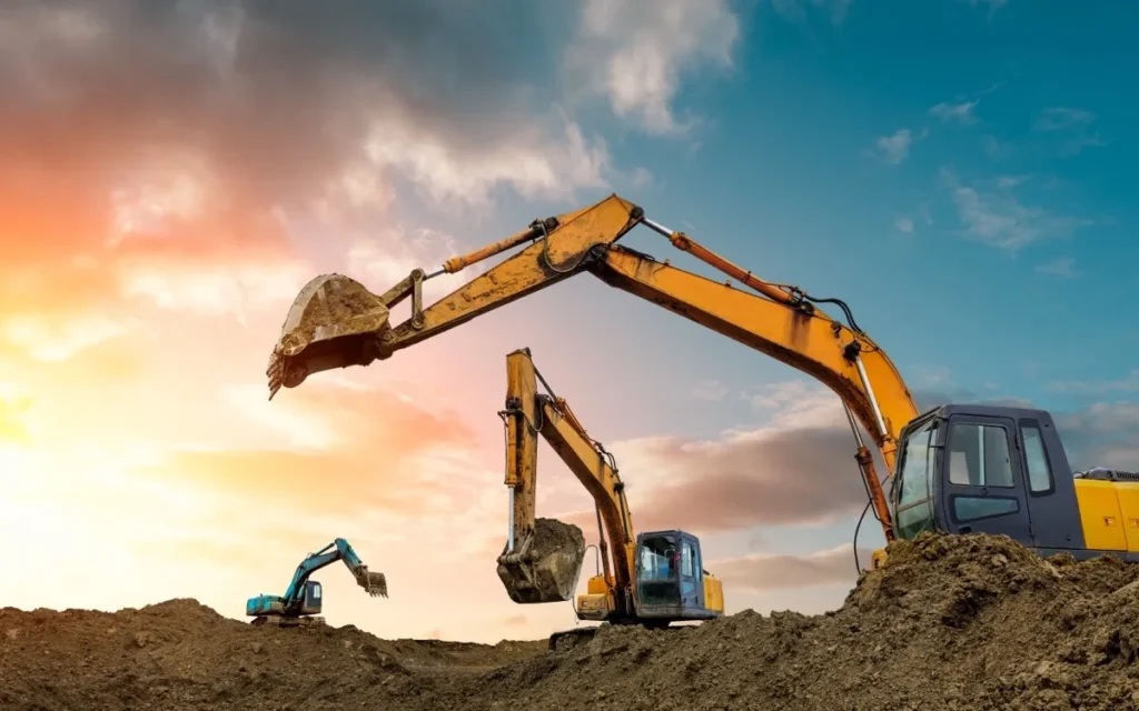 Excavators working on a construction site at sunset